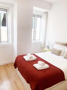 a white bedroom with two towels on a bed at Lisbon Central Apartment with Terrace in Lisbon