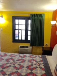 a bedroom with a bed and a window with a fan at Holly Motel Southampton in Southampton