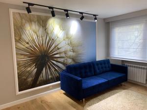 un divano blu in una stanza con un grande dipinto di Studio Nad Morzem a Danzica