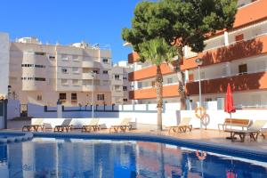 a swimming pool with lounge chairs and a building at La Familia Gallo Rojo in El Campello