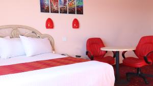 1 dormitorio con 1 cama, 2 sillas rojas y mesa en Crystal Star Inn Edmonton Airport with free shuttle to and from Airport, en Leduc