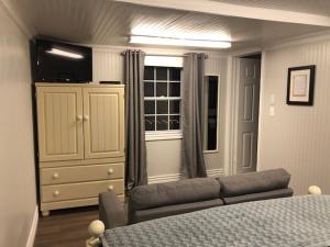 a bedroom with a couch and a dresser and a window at By The Sea Tourist Home in Bonavista