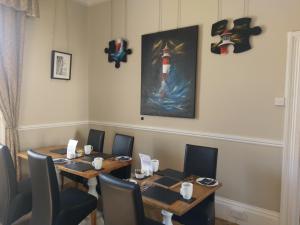 a dining room with two tables and chairs and a painting at Gallery Guest House in Plymouth