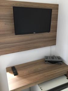 a tv on a wooden shelf with a remote control at Hotel Renavi in Além Paraíba