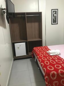 um quarto com uma cama com um cobertor vermelho em Hotel MM AEROPORTO BRASÍLIA em Núcleo Bandeirante
