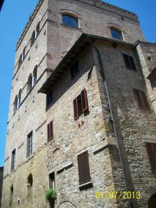 un edificio alto de ladrillo con ventanas y una torre en La Torre Nomipesciolini en San Gimignano