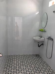a white bathroom with a sink and a mirror at Bí Homestay in Mui Ne