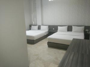 Camera con 2 letti e cuscini bianchi di Tulip Guest House a Bandung