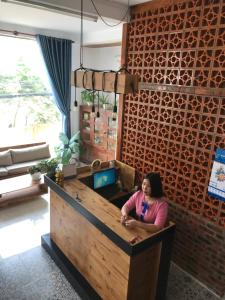 Eine Frau, die an einer Theke in einem Zimmer sitzt. in der Unterkunft Thao Trang Hotel in Dong Hoi