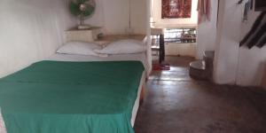 Habitación pequeña con cama y manta verde. en Wildebeeste Lamu, en Lamu