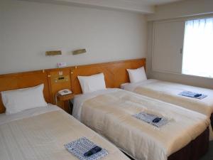 東京にあるホテル機山館のベッド2台と窓が備わるホテルルームです。