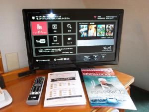 uma televisão e dois livros sobre uma mesa com um controle remoto em Hotel Kizankan em Tóquio