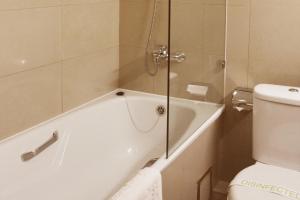 y baño con bañera, aseo y ducha. en The Corporate Hotel en Ulán Bator
