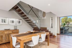 a dining room with a wooden table and white chairs at Byron Bay Accom Unit 2 21-25 Fletcher Street - Casablanca at Bogarts in Byron Bay