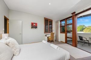 a bedroom with a white bed and a table and chairs at Byron Bay Accom Unit 2 21-25 Fletcher Street - Casablanca at Bogarts in Byron Bay