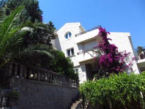 a white house with a fence and purple flowers at Apartments and Rooms Teona in Budva