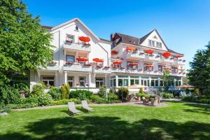 un grand bâtiment blanc avec des parasols rouges dans une cour dans l'établissement Hotel Noltmann-Peters, à Bad Rothenfelde