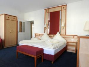 シュヴァインフルトにあるAlte Reichsbankの大きなベッドと赤いスツールが備わるホテルルームです。