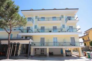 a tall white building with balconies and a tree at Hotel Stefan Room & Breakfast in Gatteo a Mare