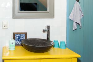 a bathroom with a black bowl sink on a yellow counter at Bed and Breakfast De Pepersteeg in Marken