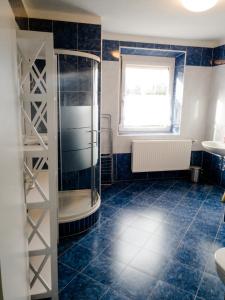 baño con ducha y azulejos azules en Ferienwohnung Koller, en Wernberg