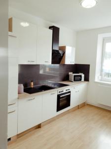 eine weiße Küche mit weißen Schränken und einer Mikrowelle in der Unterkunft Ferienwohnung Koller in Wernberg