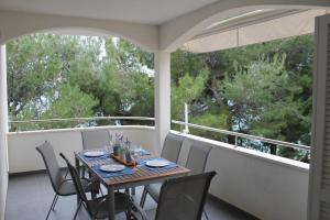 a table and chairs on a balcony with trees at Apartman M&M in Stara Novalja