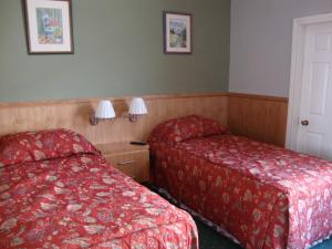 two beds in a hotel room with red sheets at Clifford House B & B in Rosslare