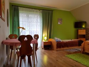 una camera da letto con pareti verdi e tavolo e sedie di Wynajem Pokoi Willa Pod Lasem a Karpacz