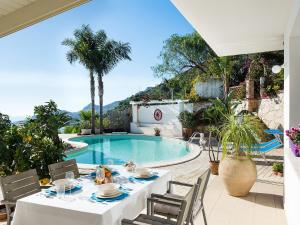 - une table et des chaises à côté de la piscine dans l'établissement Belvilla by OYO Villa with panoramic sea view pool, à Letojanni