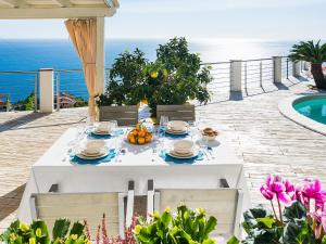 - une table blanche avec de la nourriture sur la terrasse dans l'établissement Belvilla by OYO Villa with panoramic sea view pool, à Letojanni