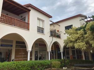 a white building with arches and a tree at Limnaria Westpark 2 bdrm apartment 122 in Paphos