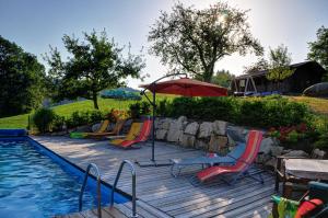 einen Pool mit Stühlen, einem Sonnenschirm und einem Tisch in der Unterkunft Dienbergerhof 5 Sterne Ferienwohnungen in Untergriesbach