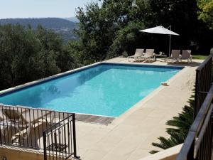 a swimming pool with chairs and an umbrella at Modern Villa with Private Pool in Cabris in Cabris