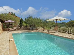 - une piscine avec un parasol, une table et des chaises dans l'établissement Provencal air conditioned villa, à Fayence