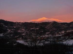 una montaña cubierta de nieve con la puesta de sol en el fondo en Val Del Rio, en Fiumalbo
