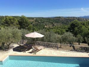 - une piscine avec un parasol, une table et des chaises dans l'établissement Provencal air conditioned villa, à Fayence