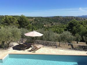 a swimming pool with an umbrella and a table and chairs at Provencal air conditioned villa in Fayence