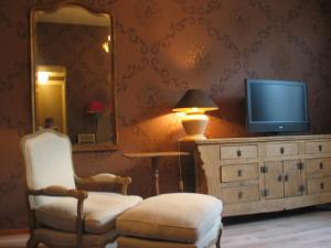 a living room with a tv and a chair and a mirror at Augusta Hotel in IJmuiden
