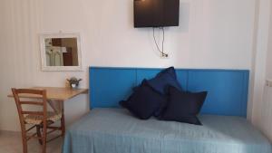 un letto con testiera blu, tavolo e specchio di Appartamentino Nadia a Monterosso al Mare