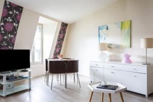 a living room with a tv and a table at Place de l'Etoile, Wagram with AC in Paris