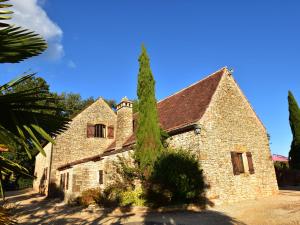 an old stone building with a tree in front of it at Beautiful holiday home with heated pool in Villefranche-du-Périgord