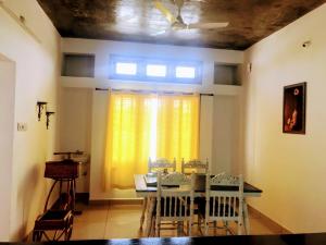 a dining room with a table with chairs and a yellow curtain at Bleu & Blanc in Puducherry