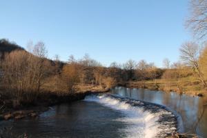 une rivière avec des rapides sur son côté dans l'établissement Le Moulin de Benechou, à Olemps