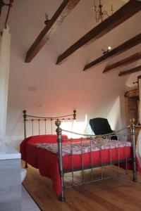 um quarto com uma cama com um cobertor vermelho em Le Moulin de Benechou em Olemps