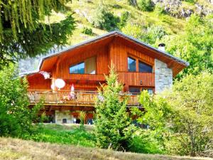 a large wooden house with a balcony on a hill at Luxurious Chalet in Champagny en Vanoise near Ski Area in Champagny-en-Vanoise