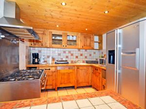 a kitchen with wooden cabinets and a stainless steel refrigerator at Luxurious Chalet in Champagny en Vanoise near Ski Area in Champagny-en-Vanoise