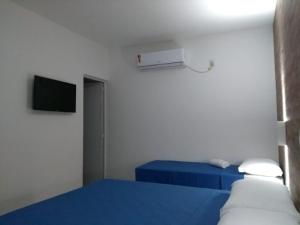 a bedroom with a blue bed and a tv at Flats das Marias in Jequia da Praia