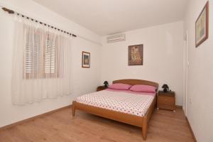 een slaapkamer met een bed met roze kussens en een raam bij Guest house Rose&Ana in Makarska