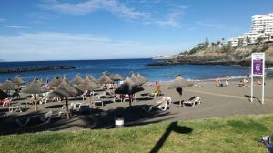 een strand met stoelen en parasols en de oceaan bij Ponderosa Holiday Studio 701 in Playa de las Americas